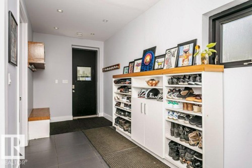Entryway featuring dark tile flooring, a built-in wooden bench, a dark-paneled door with a rectangular window insert, and recessed ceiling lighting - 9035 Saskatchewan Drive, Edmonton, AB 