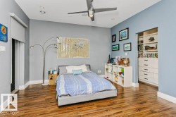 Room featuring wood-finish flooring, light blue walls, and a recessed custom closet system with shelving and multiple drawers - 