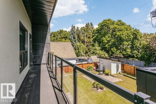 Balcony with dark paneling, wood-finish flooring, and glass railing - 9035 Saskatchewan Drive, Edmonton, AB 