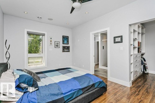 Spacious room featuring wood-finish flooring, a contemporary ceiling fan, recessed lighting, and a built-in closet system with open shelving and drawers - 9035 Saskatchewan Drive, Edmonton, AB 