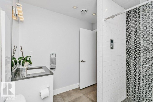 Bathroom featuring a frameless glass shower enclosure with white subway tile and a mosaic tile accent wall - 9035 Saskatchewan Drive, Edmonton, AB 