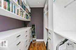 Custom organizational system featuring white cabinetry, integrated shelving, ample drawer storage with polished hardware, and wood-finish flooring - 