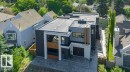 Contemporary architectural design featuring a flat roofline, dark grey and white exterior finishes, large rectangular windows, a stone-clad entrance, and a paved driveway - 9035 Saskatchewan Drive, Edmonton, AB 