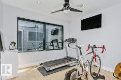 Dedicated fitness space featuring a large picture window, ceiling fan, recessed lighting, wall-mounted television, and light-colored flooring - 