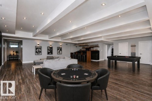 Spacious recreation room featuring recessed lighting, exposed ceiling beams, wood-finish flooring, and a built-in wet bar with shelving - 9035 Saskatchewan Drive, Edmonton, AB 