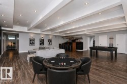 Spacious recreation room featuring recessed lighting, exposed ceiling beams, wood-finish flooring, and a built-in wet bar with shelving - 