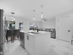 Contemporary kitchen island with a white solid surface countertop, undermount sink, and black matte faucet - 