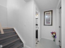 Staircase with wood-finish treads and white risers, featuring a partial handrail - 