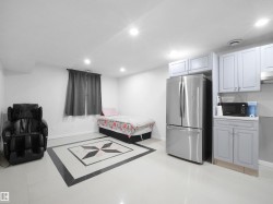 Open concept space featuring light-toned flooring with a central dark-and-light tile inlay - 