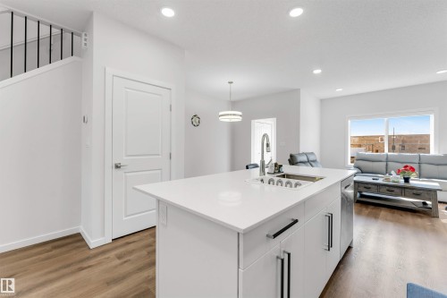 Contemporary kitchen island featuring a stainless steel sink, pull-down faucet, and white countertop - 788 Mattson Drive, Edmonton, AB 