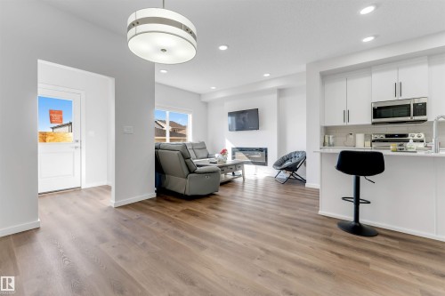 Open-concept living space featuring wood-finish flooring, recessed lighting, and a contemporary linear fireplace - 788 Mattson Drive, Edmonton, AB 