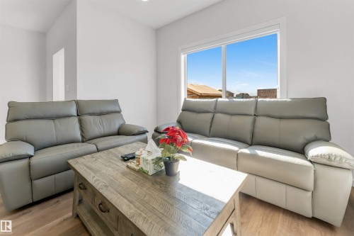 Spacious room featuring wood-finish flooring, a large window, recessed lighting, and crisp white walls - 788 Mattson Drive, Edmonton, AB 