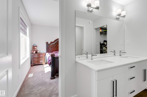 Contemporary bathroom vanity featuring dual undermount sinks, a wide mirror, and vanity lighting - 788 Mattson Drive, Edmonton, AB 