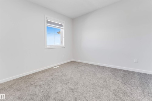 Light-filled room featuring a single window with white trim, neutral wall paint, gray carpeting, and white baseboards - 788 Mattson Drive, Edmonton, AB 