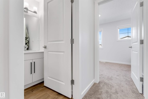 Open white paneled door revealing a room with plush carpet flooring, white walls, and two windows - 788 Mattson Drive, Edmonton, AB 