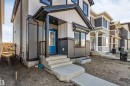 Contemporary exterior featuring a bright blue entry door, covered porch, concrete steps, and a complementary two-tone siding design - 788 Mattson Drive, Edmonton, AB 