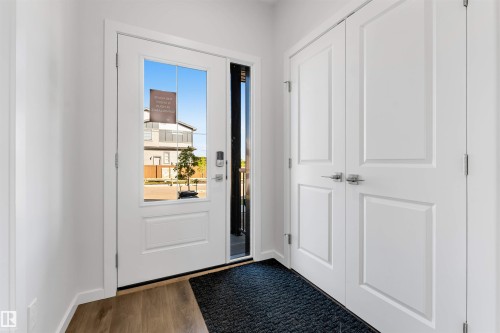 Entryway featuring wood-finish flooring, a white paneled entry door with clear glass, a sidelight, and a modern digital lock - 788 Mattson Drive, Edmonton, AB 