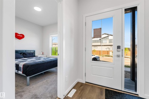 Entryway featuring a white door with clear glass panels, a full-length sidelight, and wood-finish flooring - 788 Mattson Drive, Edmonton, AB 