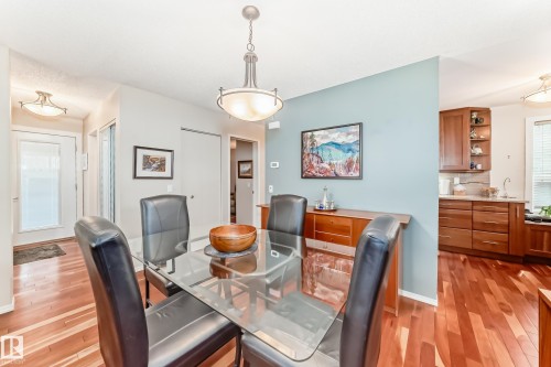 Dining area featuring wood-finish flooring, a contemporary chandelier, and a light blue accent wall - 7930 111 Street, Edmonton, AB - Indoor Photo Showing Dining Room