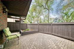 Private patio, accessed from living room.  Paved patio featuring a raised garden bed, brown privacy fencing, and a brick exterior wall with an attached outdoor light fixture - 