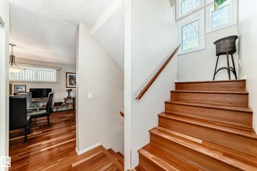 Hardwood staircase featuring a wood handrail and multiple large windows - 7930 111 Street, Edmonton, AB - Indoor Photo Showing Other Room