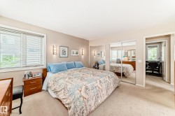 Carpeted bedroom featuring a large window with blinds, wall sconces, and mirrored closet doors - 