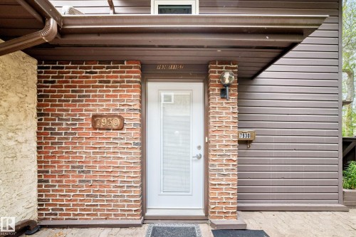 Entryway featuring a white door with transom lites, brick facade, horizontal siding, and an attached wall sconce - 7930 111 Street, Edmonton, AB - Outdoor With Exterior
