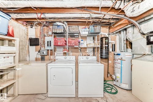 Dedicated laundry area featuring a washer and dryer, utility sink, water heater, and exposed ceiling joist.  Freezer is included - 7930 111 Street, Edmonton, AB - Indoor Photo Showing Laundry Room