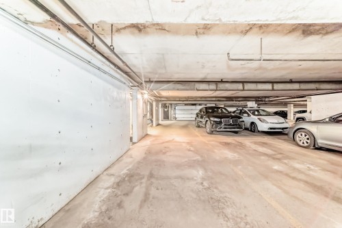 Underground parking area featuring concrete flooring, exposed overhead piping, and a bright light source illuminating the space - 7930 111 Street, Edmonton, AB - Indoor Photo Showing Garage
