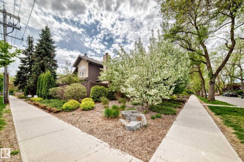 Stone and siding exterior with a prominent chimney, surrounded by mature trees and shrubs - 7930 111 Street, Edmonton, AB - Outdoor