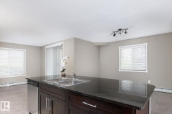 Kitchen island with dark cabinetry, stainless steel double sink, and integrated dishwasher - 