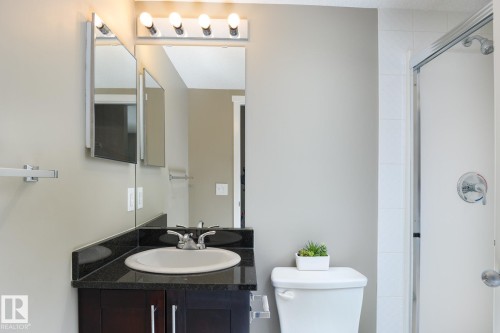 Bathroom featuring a dark wood-finish vanity with a dark countertop, an undermount sink, and chrome fixtures - 102 25 Element Dr, St. Albert, AB 