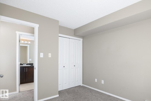 Neutral-toned room featuring light gray carpeting, white baseboards, and a bi-fold closet with white paneled doors - 102 25 Element Dr, St. Albert, AB 