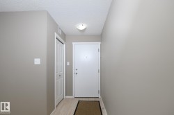 Inviting entryway featuring a solid white door, light wood-finish flooring, neutral wall tones, and a functional bi-fold closet door - 