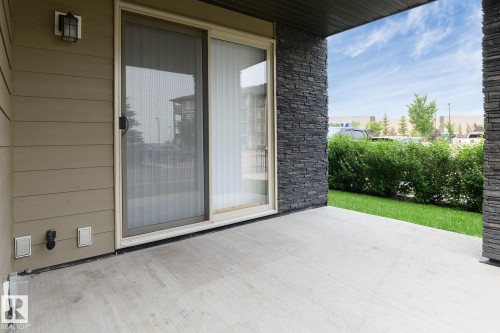 Concrete patio with stone accent wall and sliding glass door - 102 25 Element Dr, St. Albert, AB 