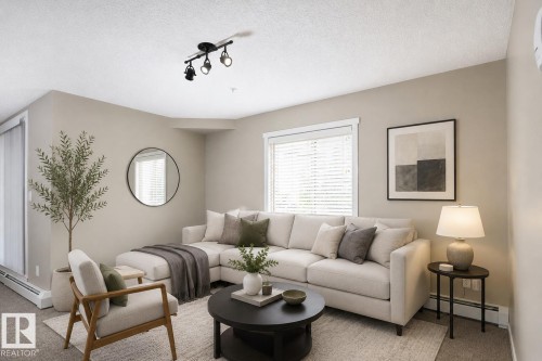 Living area featuring neutral wall tones, track lighting, and a large window with blinds - 102 25 Element Dr, St. Albert, AB 