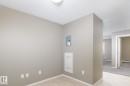 Light wood-finish flooring extending into an open doorway, neutral wall paint, white baseboards, and a flush-mount ceiling light - 102 25 Element Dr, St. Albert, AB 