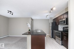 Kitchen featuring dark wood-finish cabinetry, stainless steel appliances, and a central island with an integrated sink and dark countertop - 