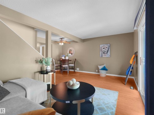 Open-concept living area with wood-finish flooring, a sliding glass door, and a dining space - 16 13833 30 Street, Edmonton, AB 