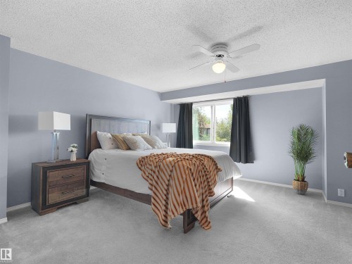 Carpeted room featuring a ceiling fan, a window with dark drapes, and light blue wall paint - 16 13833 30 Street, Edmonton, AB 