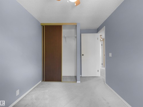 Carpeted room with light blue walls, featuring a sliding closet door with a wood-finish panel - 16 13833 30 Street, Edmonton, AB 
