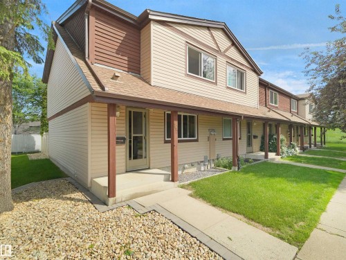 Two-story residence featuring light-colored siding with contrasting brown trim and a covered front porch with supporting posts - 16 13833 30 Street, Edmonton, AB 