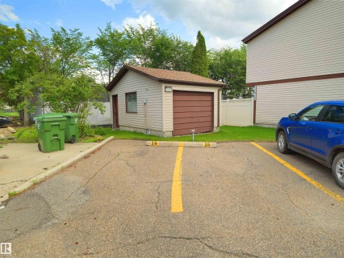 Detached utility shed with a brown roll-up door and side entry - 16 13833 30 Street, Edmonton, AB 