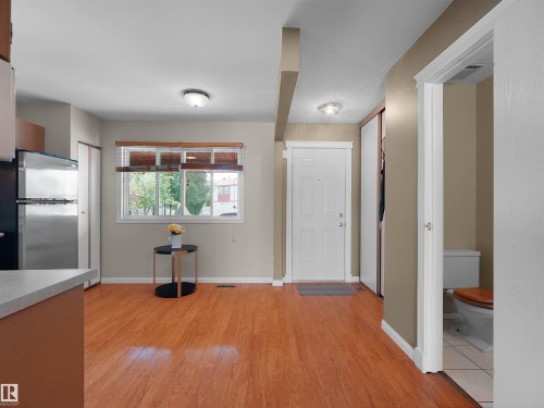 Entryway with wood-finish flooring, a white paneled door, and a built-in closet with sliding doors - 16 13833 30 Street, Edmonton, AB 