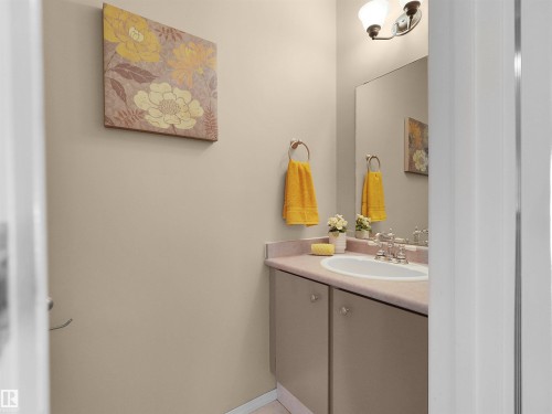 Bathroom vanity with an integrated sink, polished chrome faucet, and bronze-finish light fixture - 16 13833 30 Street, Edmonton, AB 