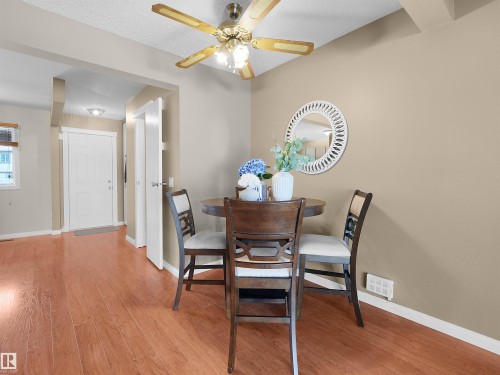 Dining area featuring wood-finish flooring, a ceiling fan with integrated lighting, and neutral wall paint - 16 13833 30 Street, Edmonton, AB 