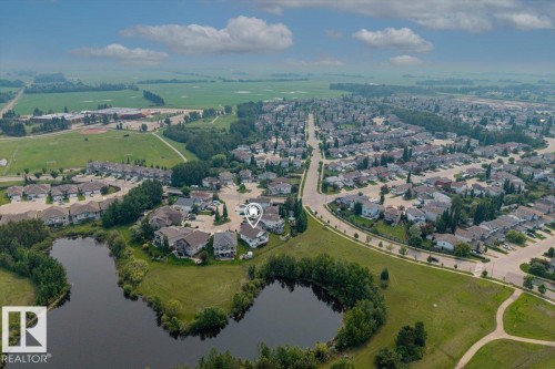 Aerial perspective showcasing a residential area bordered by open fields and natural water features - 215 Westerra Point(E), Stony Plain, AB 