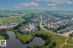 Aerial perspective showcasing a residential area bordered by open fields and natural water features - 