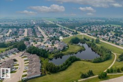 Aerial perspective showcasing a residential area with a prominent pond and surrounding green space - 