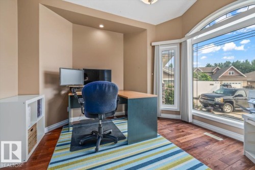 Room featuring wood-finish flooring, a built-in recessed light, and a large arched window - 215 Westerra Point(E), Stony Plain, AB 